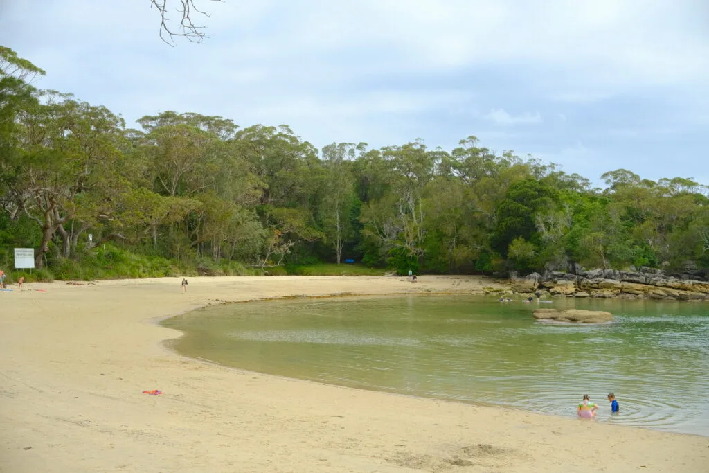Sandy cove with two children playing in the water.