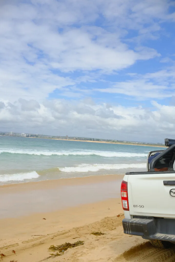 DSCF1413-2 Waves crashing with parked ute on sand.