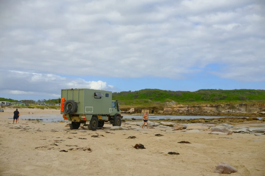 Unimog truck parked on sand in the cove.