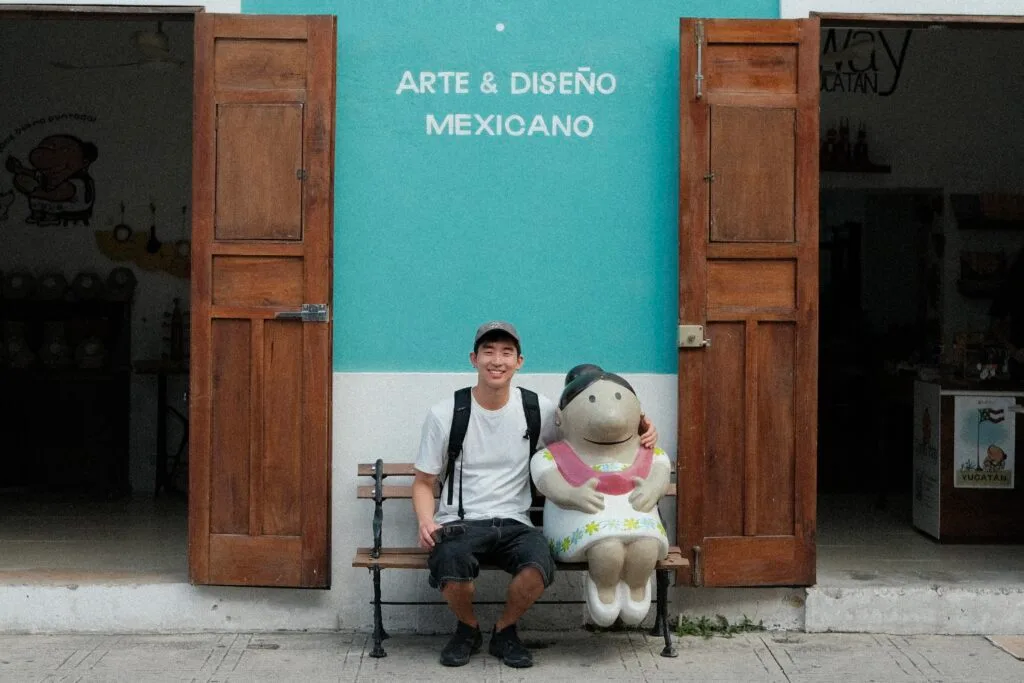 Me smiling and posing on a bench next to a statue of a Merida local 