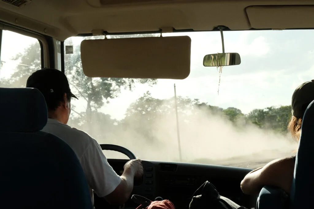 Dusty rural road in Guatemala through the bus driver's view