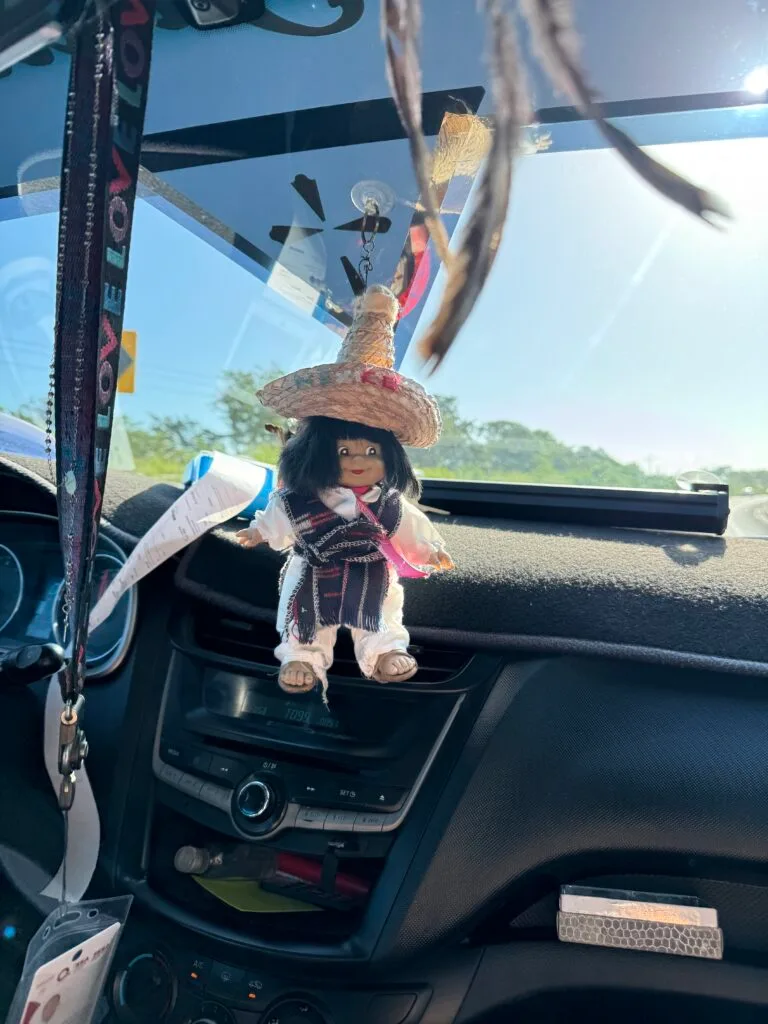A sombrero de charro wearing gremlin trinket dangles off the dash in my taxi