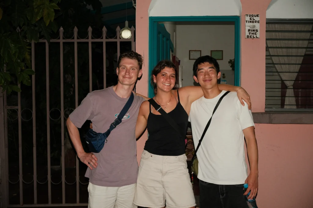 3 friends smiling and holding each other close in Flores at night