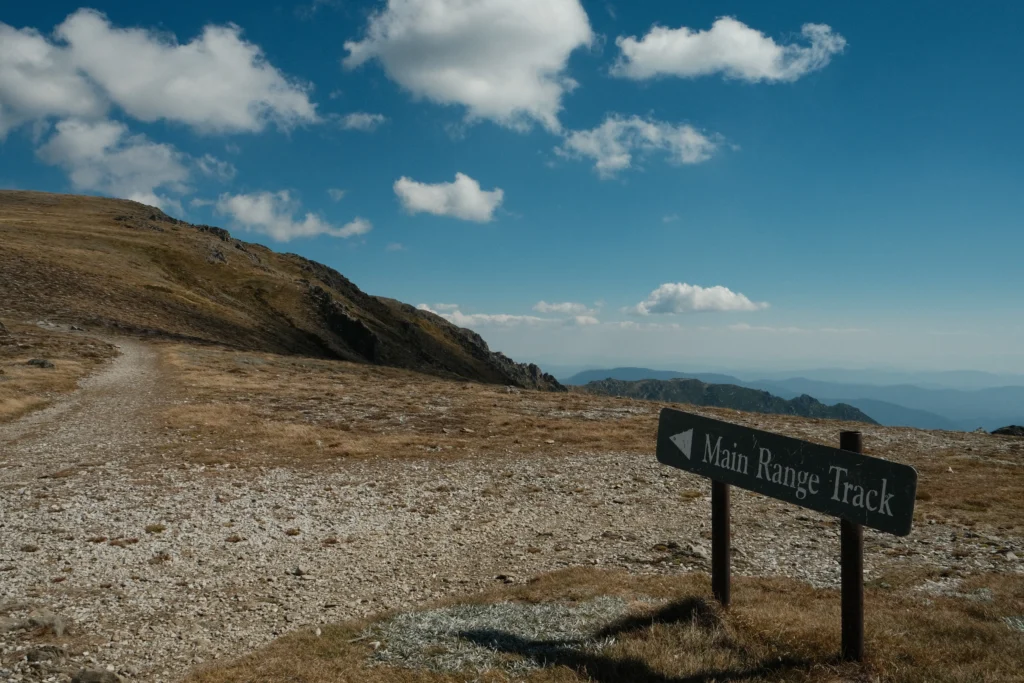 Main Range Track sign in front of mountains.
