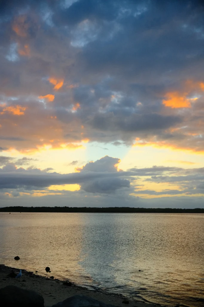 Serene sunset piercing through a cloud over the ocean