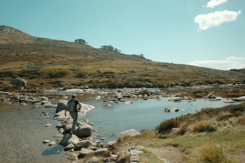 Hiker making his way through the lake crossing on the Main Range Track.