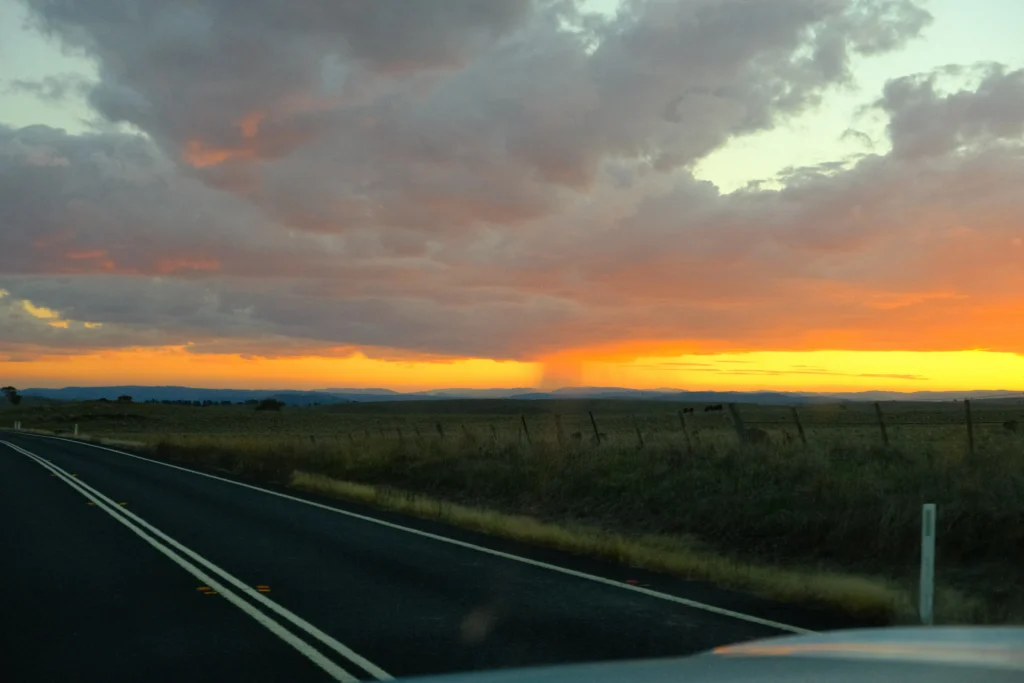Rainclouds pouring over a golden field during sunset on the road to Mount Kosciuszko.