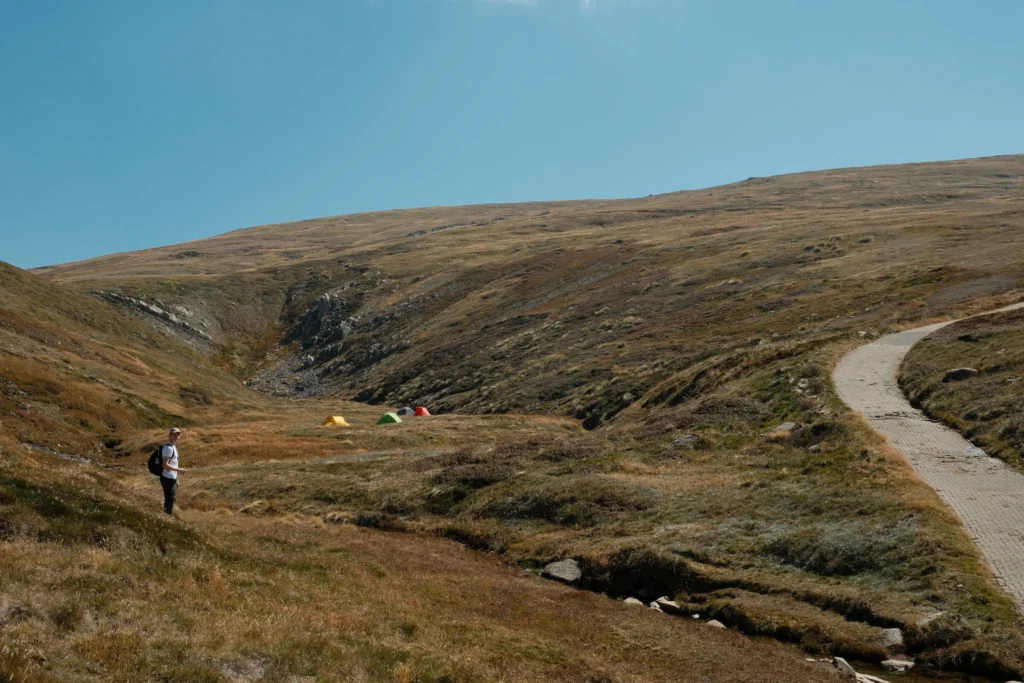 Four colourful tents and my friend in the foreground of the main range trail.