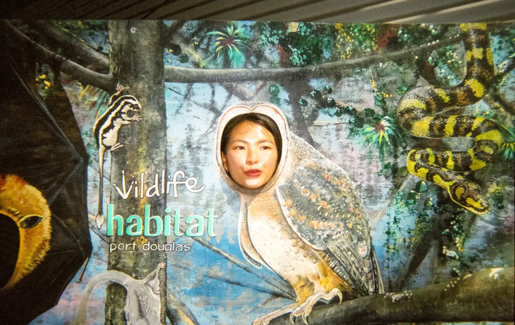 girl with her head through the wildlife habitat sign, posing as an owl