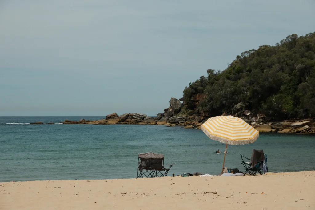 A yellow beach umbrella perched alone on Wattamolla beach